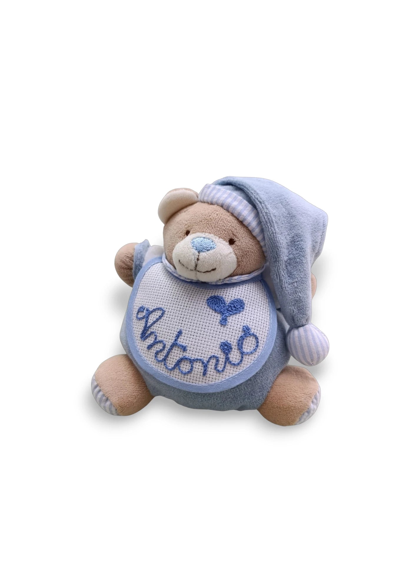 Orsetto peluche per neonati con pigiamino e cappellino a righe. Il peluche ha un bavaglino bianco in tela Aida per ricamo.